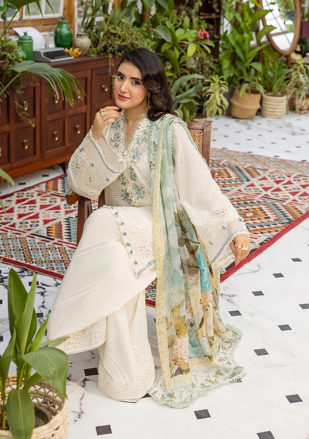 Woman in a traditional outfit sitting in a decorated room with plants