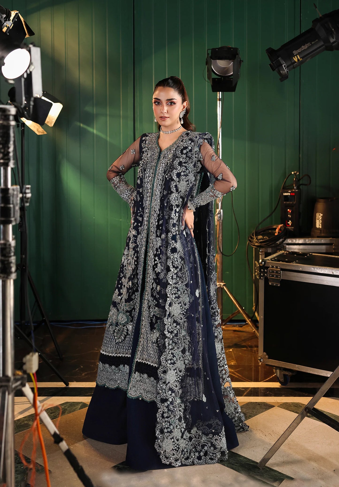 Woman in a dark blue and white floral traditional outfit standing in a photo studio with green screen background with Elaf Stardom Handwork.