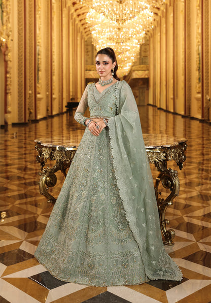 Woman in a light green embroidered traditional outfit standing in an opulent room with gold decor in with Elaf Stardom Handwork