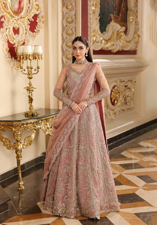 Woman in a traditional pink and gold embroidered outfit standing in an ornate room with Elaf Stardom Handwork