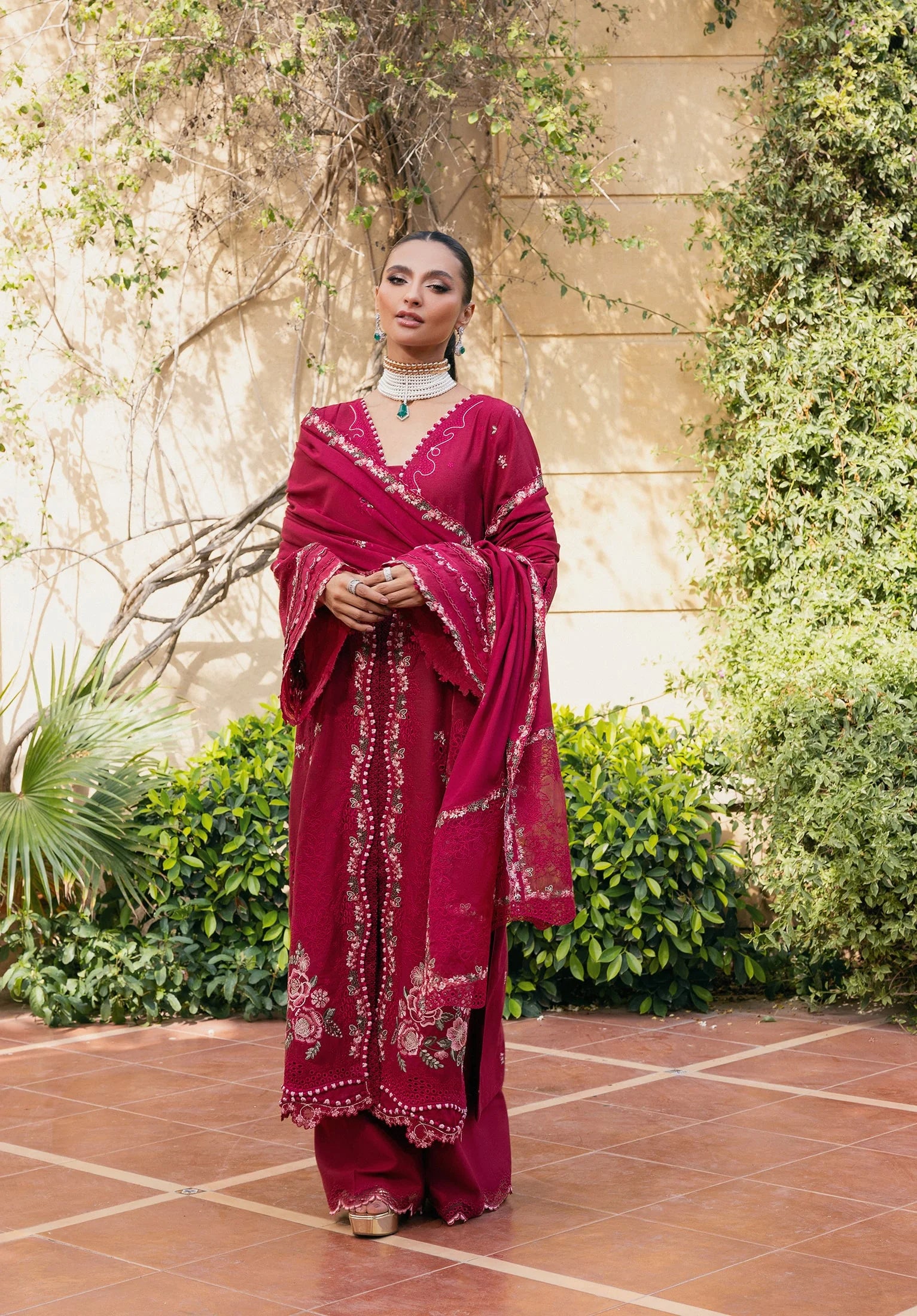 Woman in a red traditional outfit standing outdoors with greenery in the background from elaf LUXURY WINTER '25
