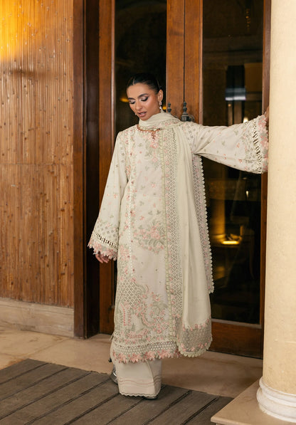 Woman in a cream embroidered traditional outfit standing indoors.